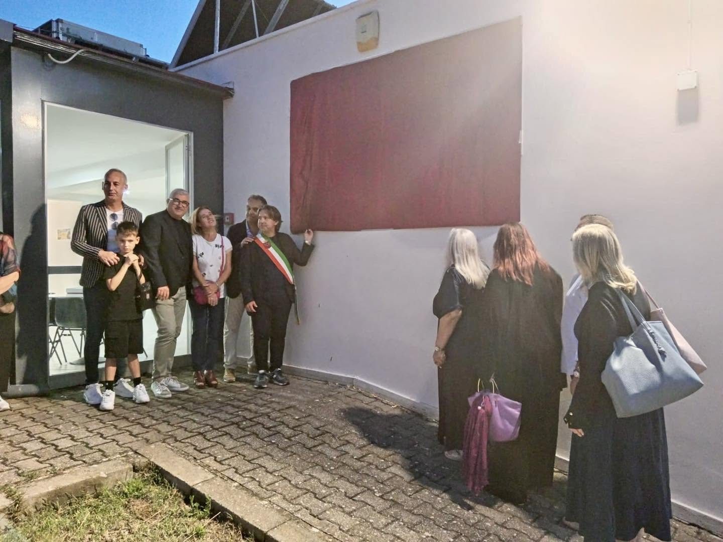 La targa dell'impianto ancora coperta dal drappo rosso prima della scopertura